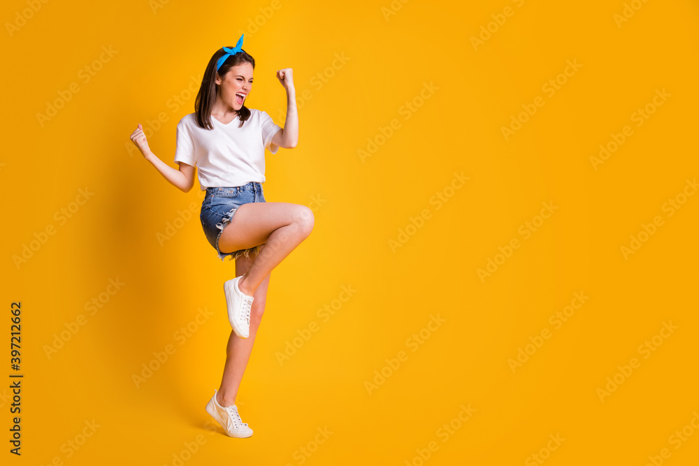 Full length body size view of charming glad cheerful brown-haired girl jumping celebrating copy space isolated over bright yellow color background Full length body size view of charming glad cheerful brown-haired girl jumping celebrating copy space isolated over bright yellow color background