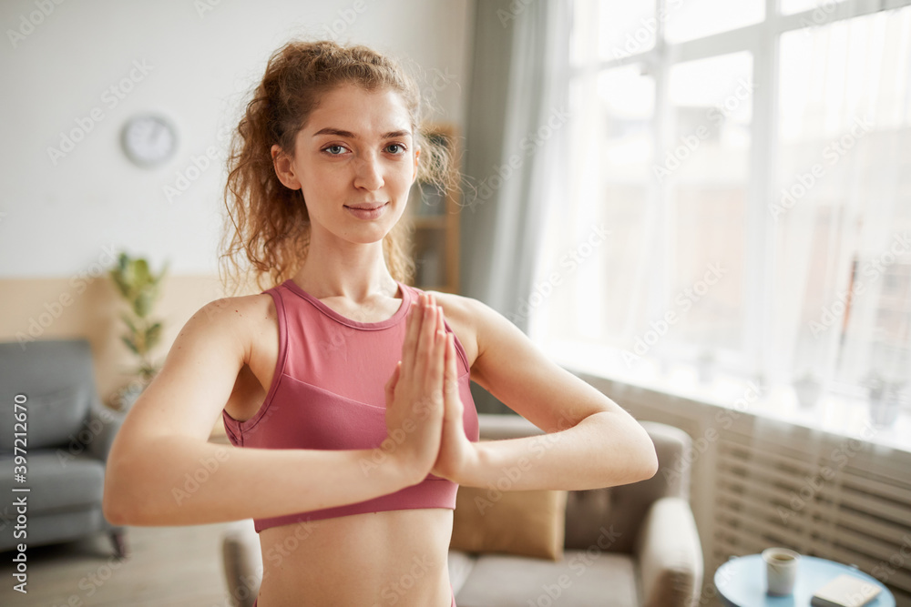Portrait of healthy woman looking at camera while standing and meditating in the room at home Portrait of healthy woman looking at camera while standing and meditating in the room at home