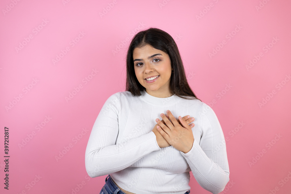 Obraz premium Young beautiful woman over isolated pink background smiling with her hands on her chest and grateful gesture on her face.