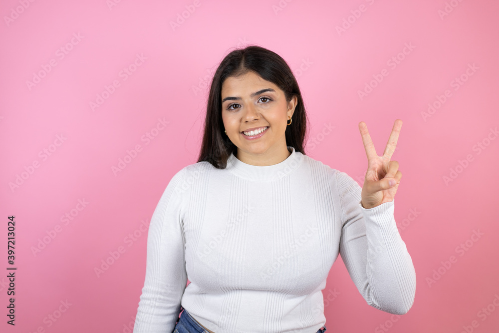 Young beautiful woman over isolated pink background showing and pointing up with fingers number two while smiling confident and happy Young beautiful woman over isolated pink background showing and pointing up with fingers number two while smiling confident and happy
