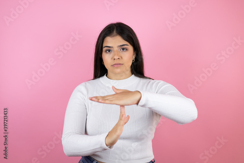 Young beautiful woman over isolated pink background Doing time out gesture with hands, frustrated and serious face