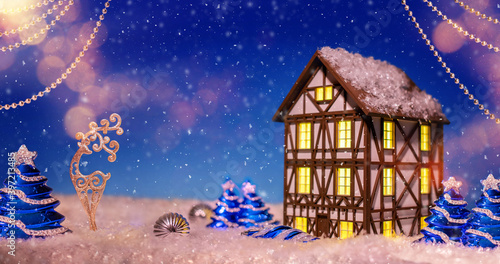 Night light in form of half-timbered house among Christmas tree decorations, garlands and deer against backdrop of a fabulous night winter landscape