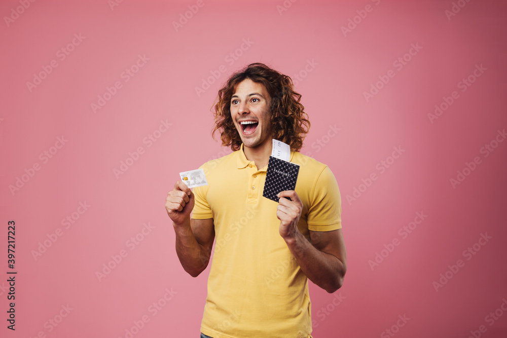 Delighted handsome guy posing with credit card and passport Delighted handsome guy posing with credit card and passport