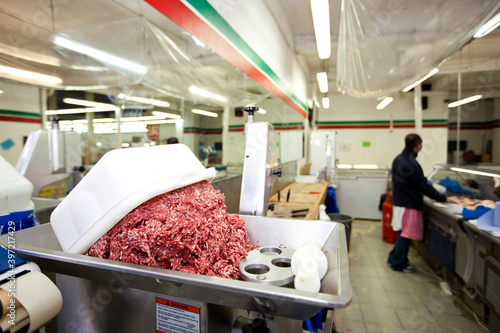 Minced meat in container with employee standing in background at store photo