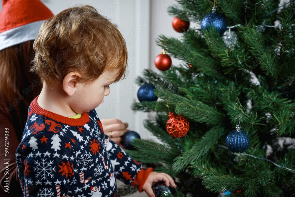 Beautiful girl with her son decorate the Christmas tree in the house. Happy family. Beautiful girl with her son decorate the Christmas tree in the house. Happy family.