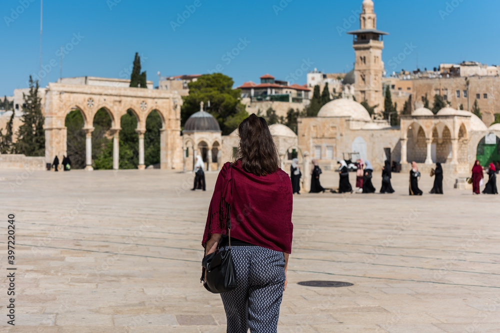 Beautiful young woman wearing scarf and walking at the square of the Golden Dome of the Rock, Qubbat al-Sakhra, an Islamic shrine located on the Temple Mount in the Old City of Jerusalem. Beautiful young woman wearing scarf and walking at the square of the Golden Dome of the Rock, Qubbat al-Sakhra, an Islamic shrine located on the Temple Mount in the Old City of Jerusalem.