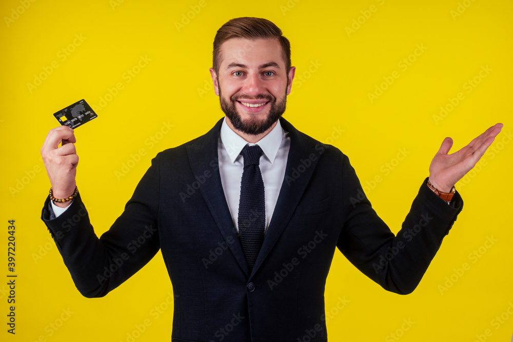Portrait of handsome young businessman holding credit card over yellow background Portrait of handsome young businessman holding credit card over yellow background