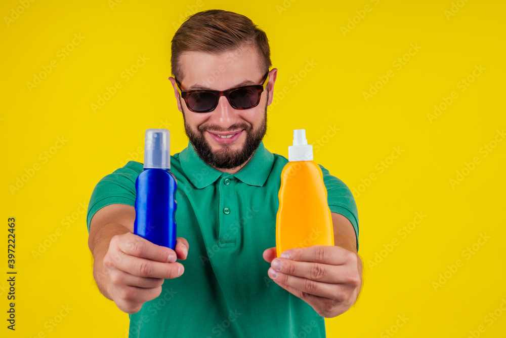 man holding bottle of sun cream in studio yellow background man holding bottle of sun cream in studio yellow background