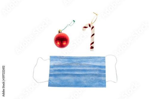 Christmas decoration on white background of candy cane, christmas red ball and protective medical face mask for Covid-19.