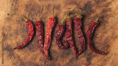 Dried, hot red chili peppers with oranges on a brown wooden kitchen board background. Sweet and spicy.