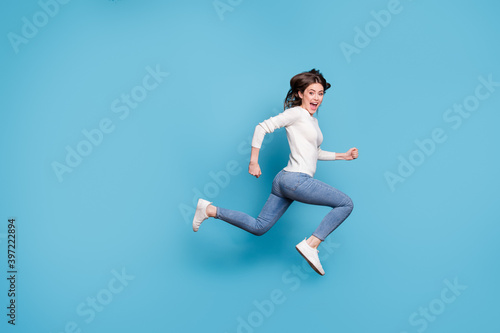 Full length photo of funny adoranle wavy lady wear white sweater jumping running isolated blue color background © deagreez