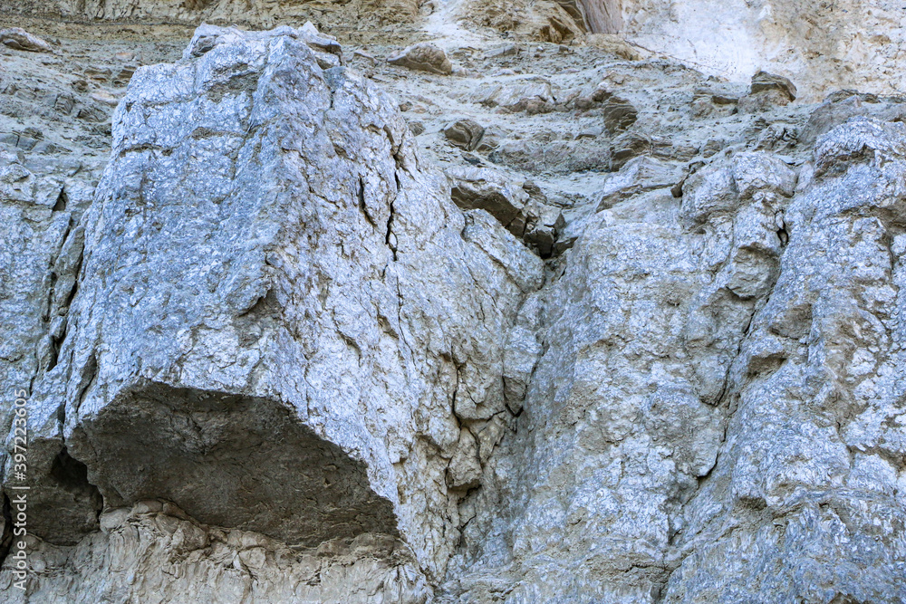 Naklejka premium sandy-gypsum cut of the earth in quarry for the extraction of gypsum. Mountain textures of different soil layers with deposits of sand, clay, gypsum, quartz and gypsum ore, after erosion.