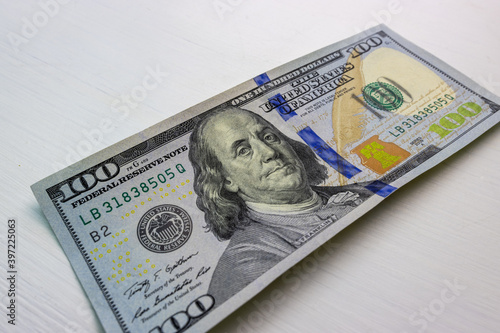 textured background of one hundred dollar bill with a portrait of us President Franklin in orange, red and black colors. blur, defocus.