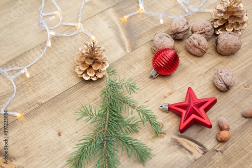 Beautiful red Christmas decorations on wooden background. Christmas background with nuts, pine cones, Christmas tree branch, red star and red ball.