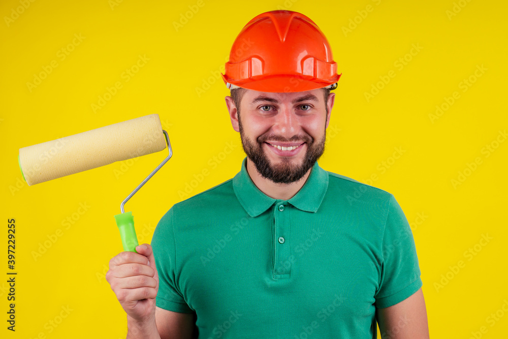 male wear a hardhat helmet painting a wall with yellow paint