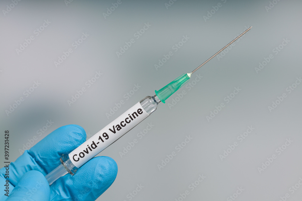 Close up of scientist's or doctor's hand in medical gloves with a syringe containing a Covid-19 serum / vaccine Close up of scientist's or doctor's hand in medical gloves with a syringe containing a Covid-19 serum / vaccine