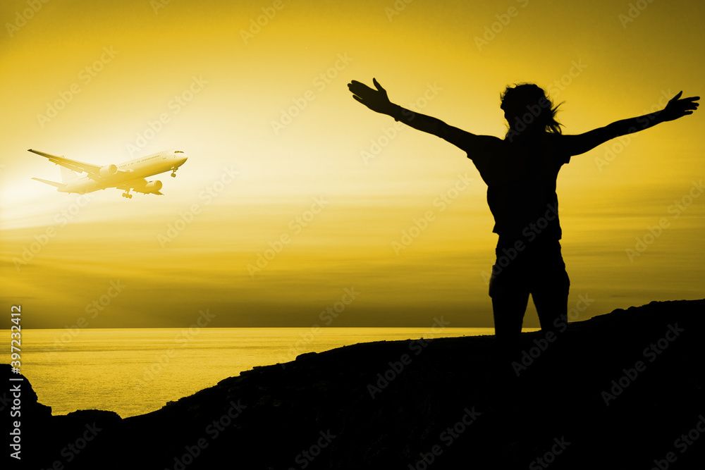 Woman on the island waving her arms to flying plane during sunset