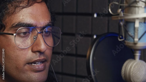 Podcast Recording. Streaming platforms. Hindi man recording voice over. An intelligent brunette indian male person records his voice.