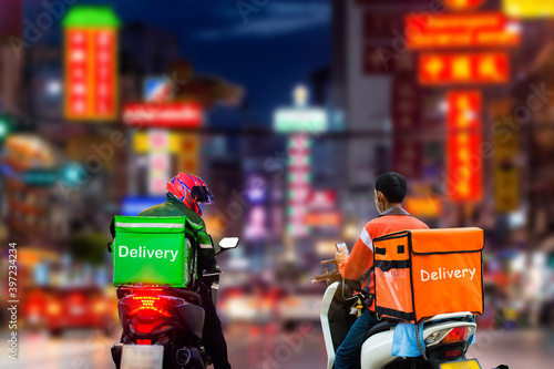 Food delivery workers are delivering food to customers who have ordered online in the city in the late evening.