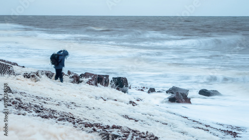 Figure of a man with a backpack in a blur in a strong wind in a storm. White sea coast. Dramatic Northern landscape