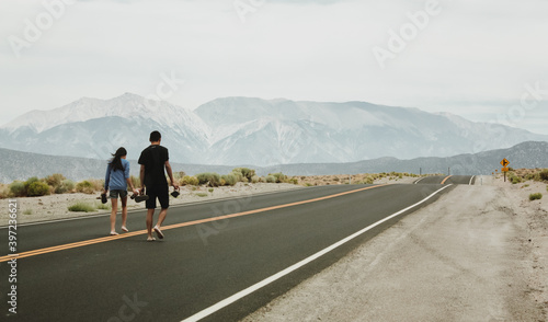 People on travel road trip walking on American highway with beautiful mountain landscape © Eline