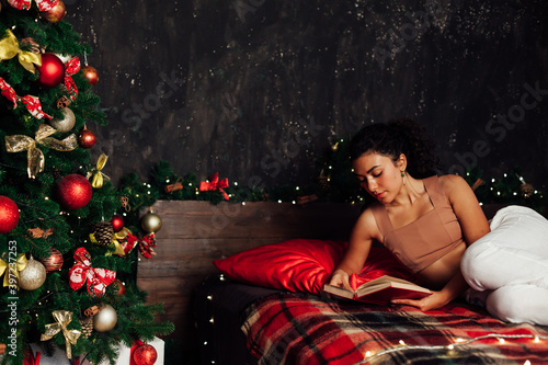Beautiful woman reads a book on a Christmas bed