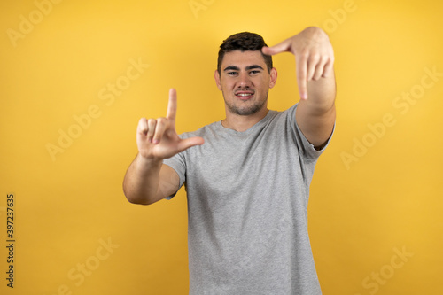 Young handsome man wearing a casual t-shirt over isolated yellow background smiling making frame with hands and fingers
