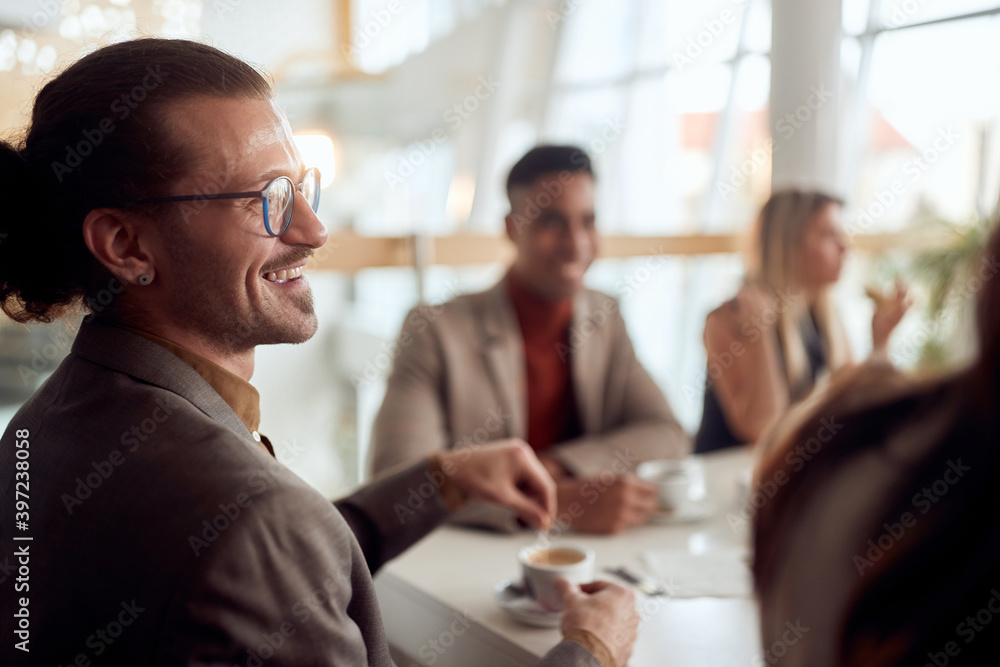 A young employee enjoying a coffee with colleagues at company's canteen. People, job, company, business concept. A young employee enjoying a coffee with colleagues at company's canteen. People, job, company, business concept.