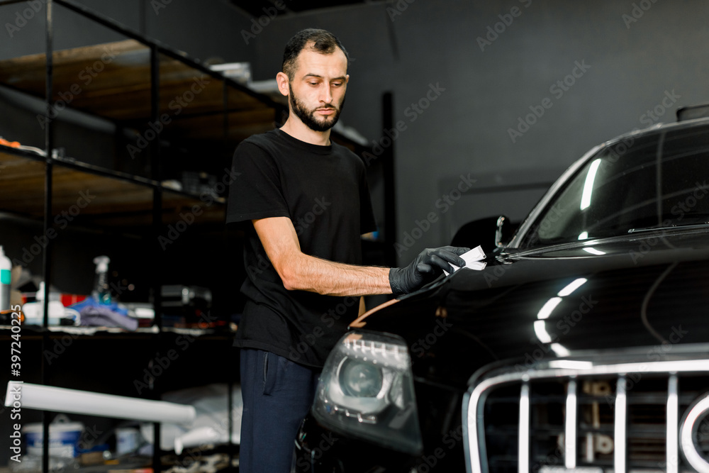 Young man, car polish service worker polishing car hood, buffing and polishing vehicle with nano ceramic composition or wax. Car detailing. Tools for polishing Young man, car polish service worker polishing car hood, buffing and polishing vehicle with nano ceramic composition or wax. Car detailing. Tools for polishing