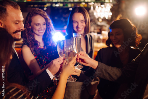 Group of happy people clinking glasses of champagne at party. Young friends celebrating winter holiday together with champagne. Party, celebration, drink, birthday concept.