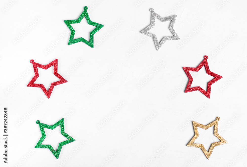 Six glittering star shaped decorations of different colors against the white background. Copy space. Minimalist festive background