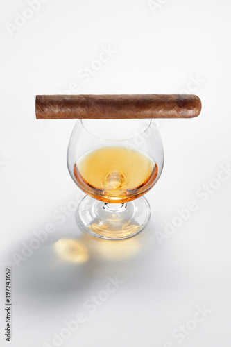 Closed up view of glass of whiskey with cigar on top on white back