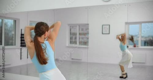 Dancer warms up infromt of the mirror wall in the white bright dance hall before rehearsal, ballet rehearsal, ballerina in the ballet studio, dance hall lesson, 4k 60p Prores HQ photo