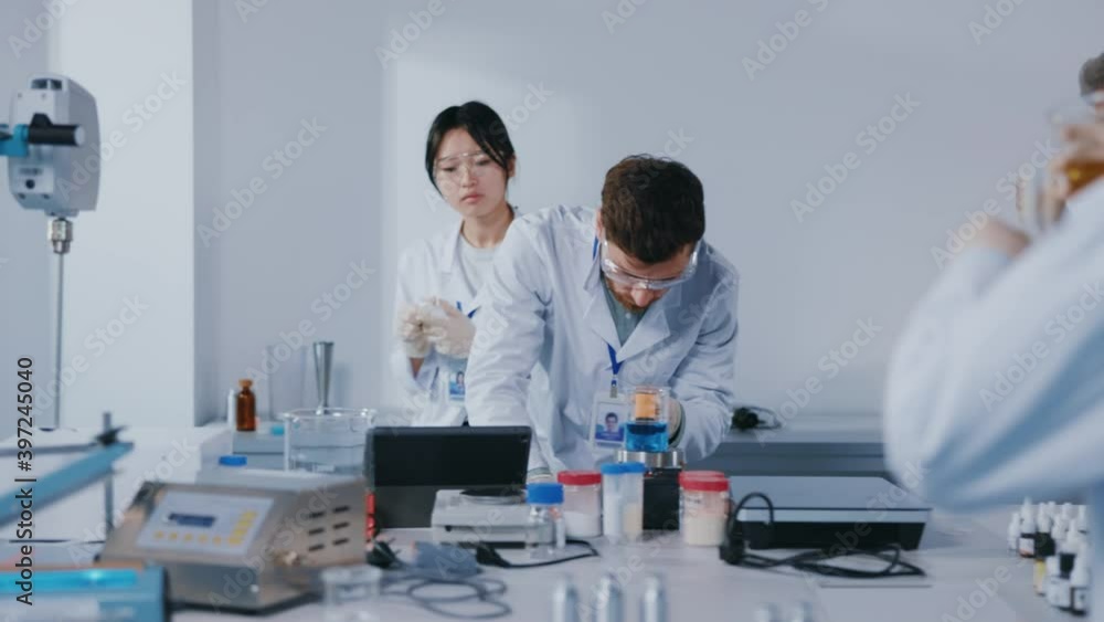Young group teamwork of scientists working biological researches under microscope in modern equipped laboratory. Virus evolution using high tech. Microbiology medical staff biotechnology. Slow motion Young group teamwork of scientists working biological researches under microscope in modern equipped laboratory. Virus evolution using high tech. Microbiology medical staff biotechnology. Slow motion