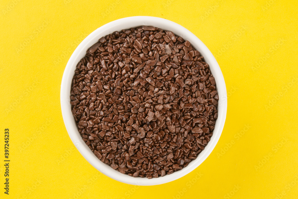 Granulated chocolate in white bowl with yellow background. Granulated chocolate in white bowl with yellow background.