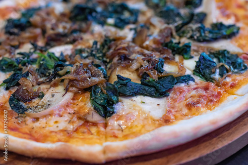 side view, italian pizza with fried onions, green spinach and mushrooms on koh samui in thailand