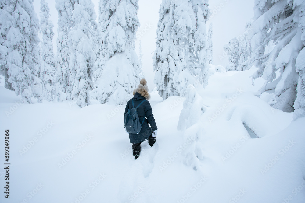 Young woman walking in deep snow in a forest