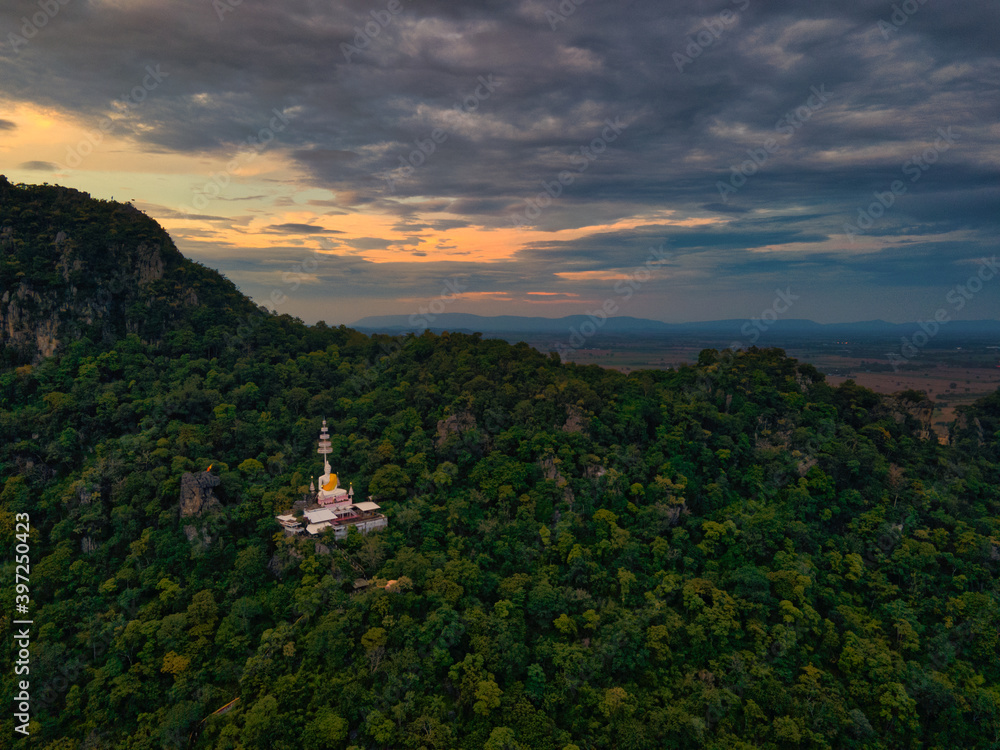 Mueang Lop Buri District, Lopburi / Thailand / October  11,2020 : Wat Pa Phatthara Piyaram. Temple with cave carvings.  Aerial View of Buddha Temple Pagoda with Mountain and Blue sky