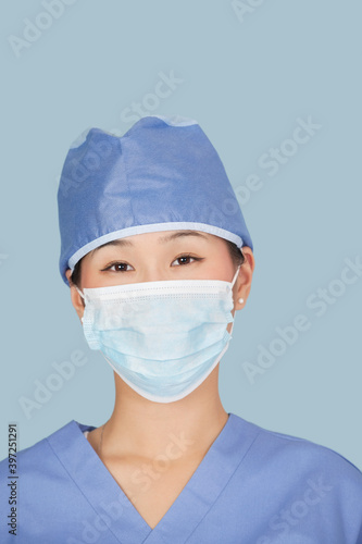 Close-up of a female surgeon wearing facemask over light blue background