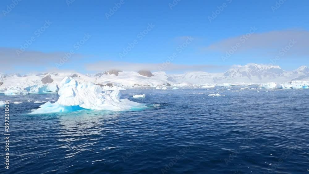 Giant floating Iceberg from melting glacier in Antarctica. View and 4K shooting from a yacht. Nature landscape famous for being heavily affected by global warming. Global Warming and Climate Change. Giant floating Iceberg from melting glacier in Antarctica. View and 4K shooting from a yacht. Nature landscape famous for being heavily affected by global warming. Global Warming and Climate Change.