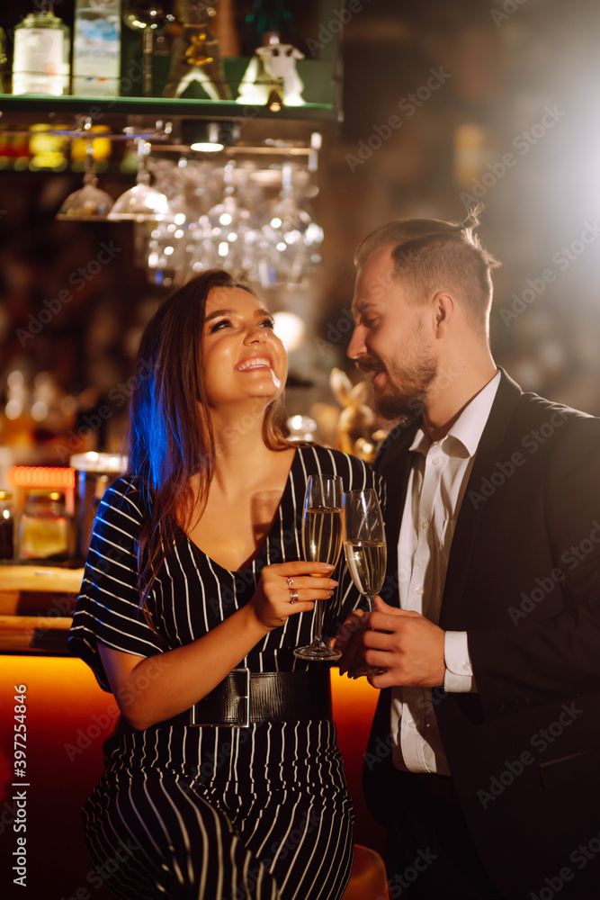 Happy loving couple enjoying having drinks together at the bar. Young man and woman clinking a glass champagne, enjoying winter holiday. Party, celebration, drink, birthday concept. Romantic evening. Happy loving couple enjoying having drinks together at the bar. Young man and woman clinking a glass champagne, enjoying winter holiday. Party, celebration, drink, birthday concept. Romantic evening.