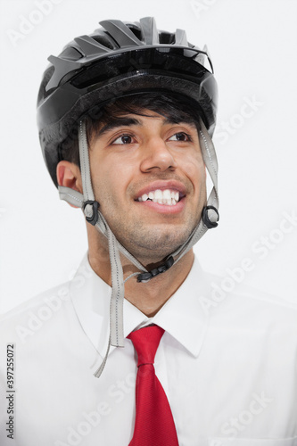 Young Indian businessman wearing cycling helmet while looking away against gray background © moodboard