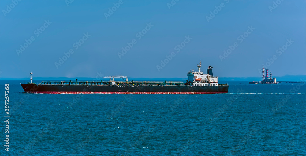 A large tanker steams past the lighthouse in the Singapore Straits in Asia in summertime