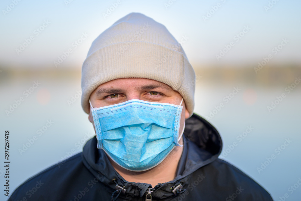 Smiling young man wearing a disposable face mask Smiling young man wearing a disposable face mask
