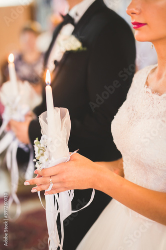 Bride and groom holding candles in church photo