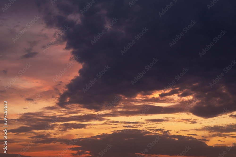 Epic dramatic sunset, sunrise on storm sky with dark clouds, orange yellow red sunlight
