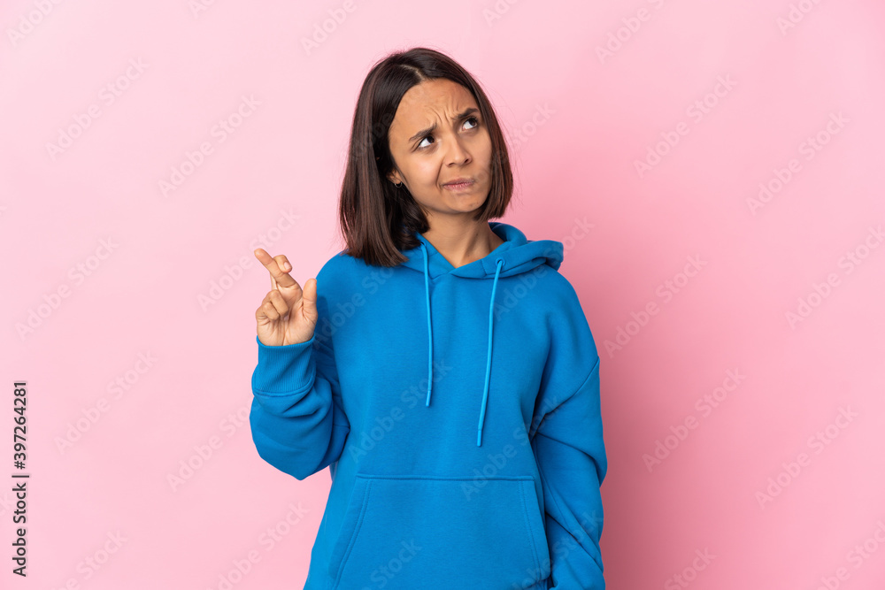 Young latin woman isolated on pink background with fingers crossing and wishing the best Young latin woman isolated on pink background with fingers crossing and wishing the best