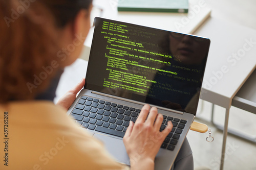 Rear view of female software programmer typing codes on laptop working with new software