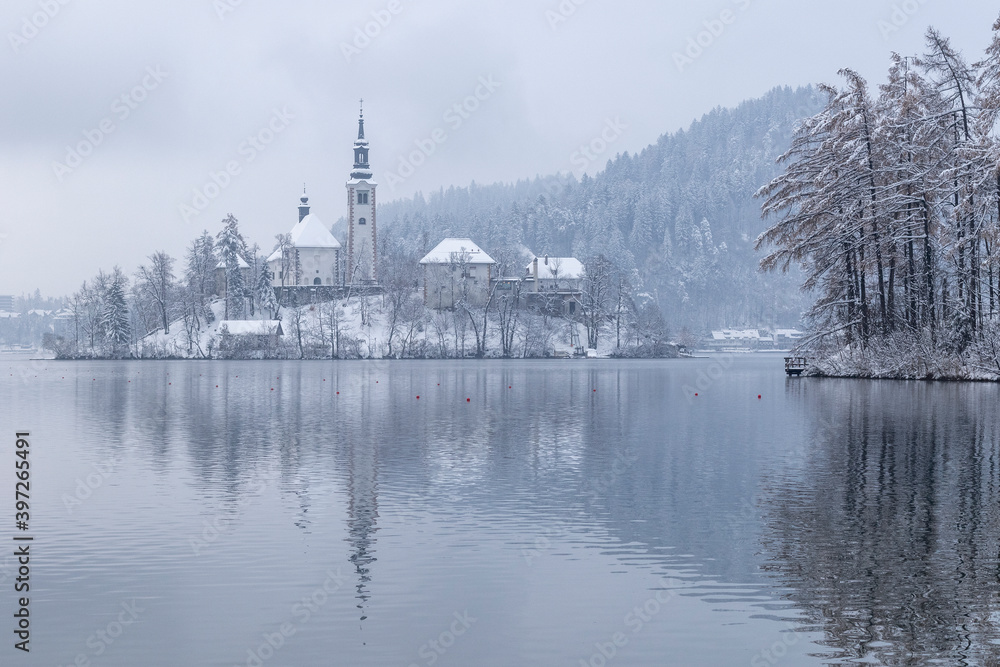 Bled lake in wintertime, scenic view of Bled Island in snow and fog, Slovenia.