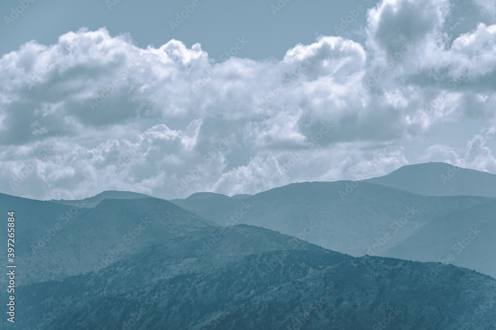 Thick clouds over mountain range, hills in blue haze